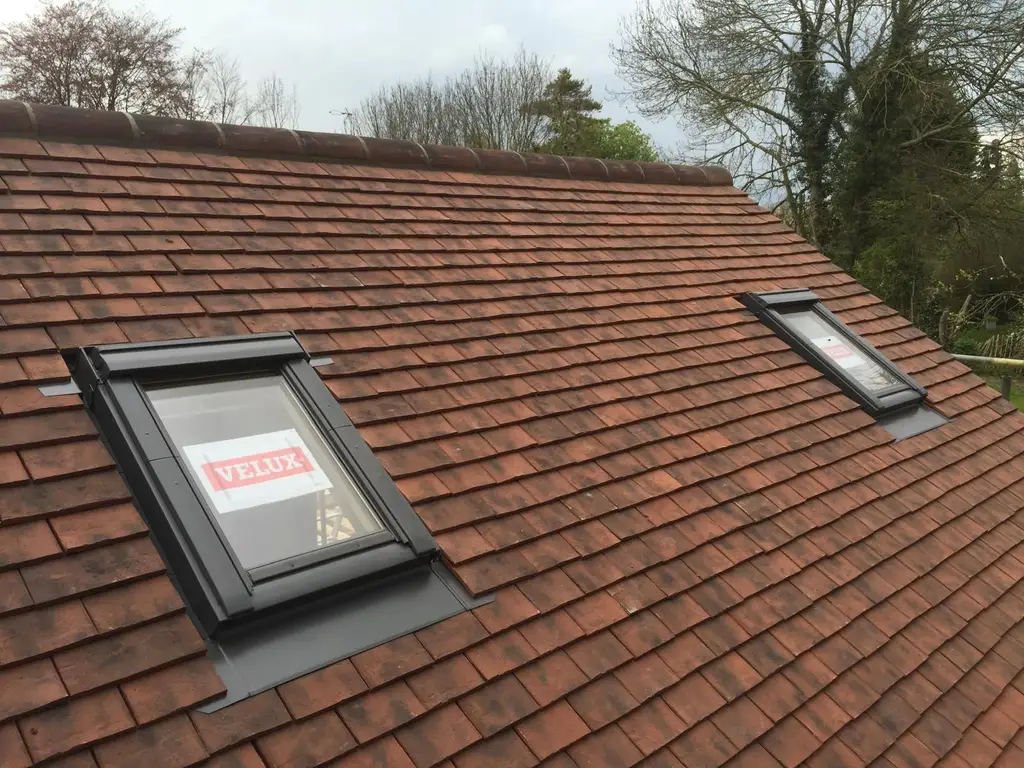 Velux roof window being installed in a clay tiled roof by Carl Dunn Building & Roofing, Cambridge
